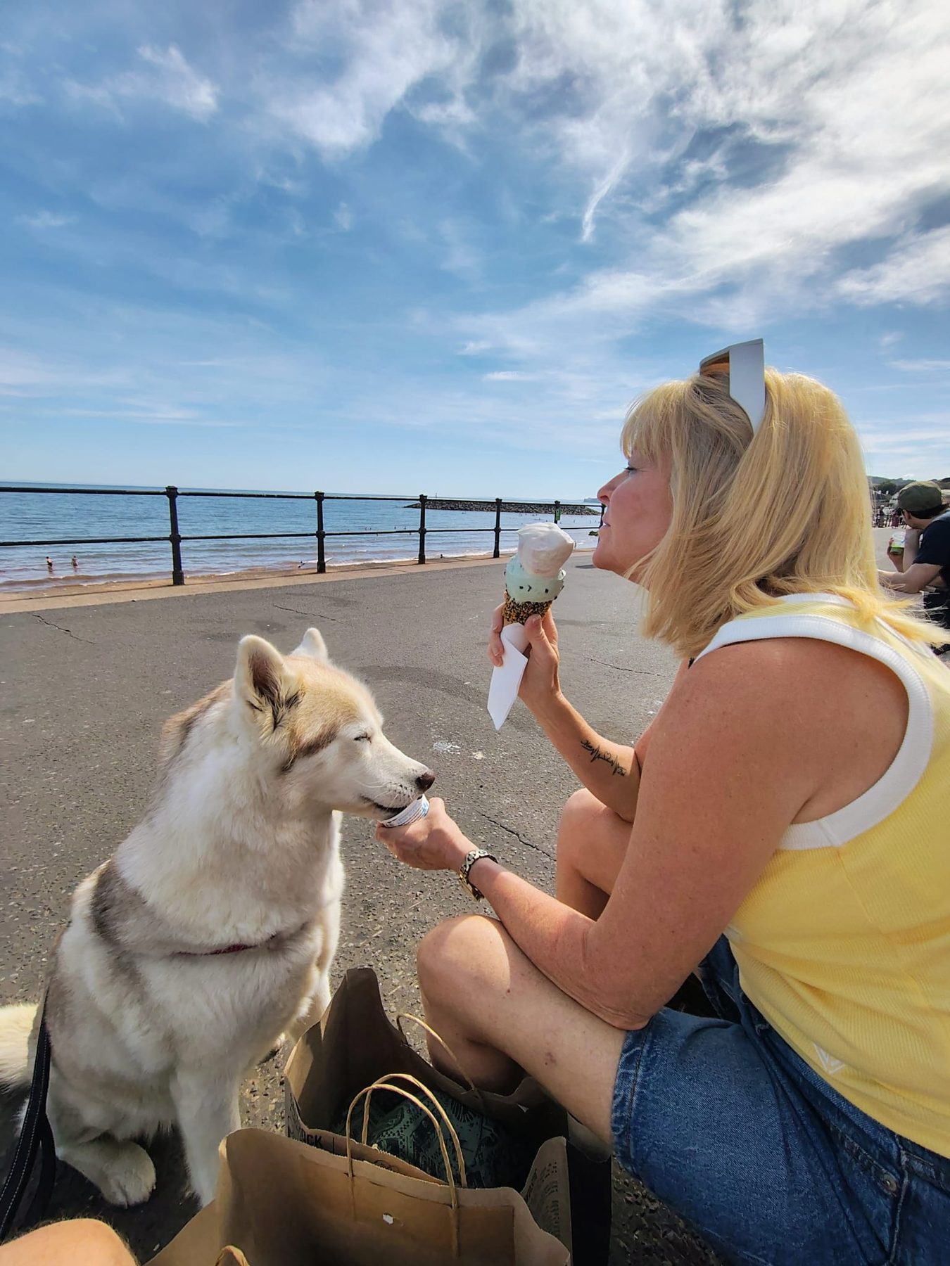 Guest and husky sharing an ice cream by the seafront railings
