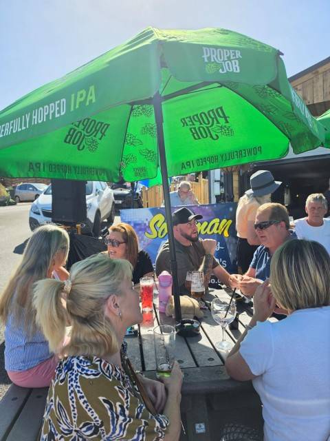 Guests enjoying live music and drinks at tables outside the park bar
